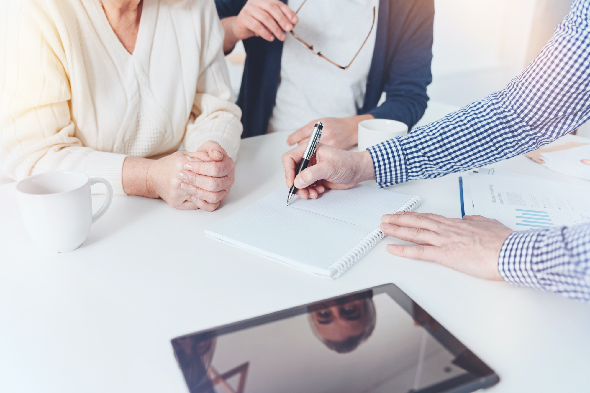 Professioanl real estate agent working with pleasant elderly couple Lets compare. Pleasant professional real estate agent drawing and meeting with nice elderly couple in the kitchen