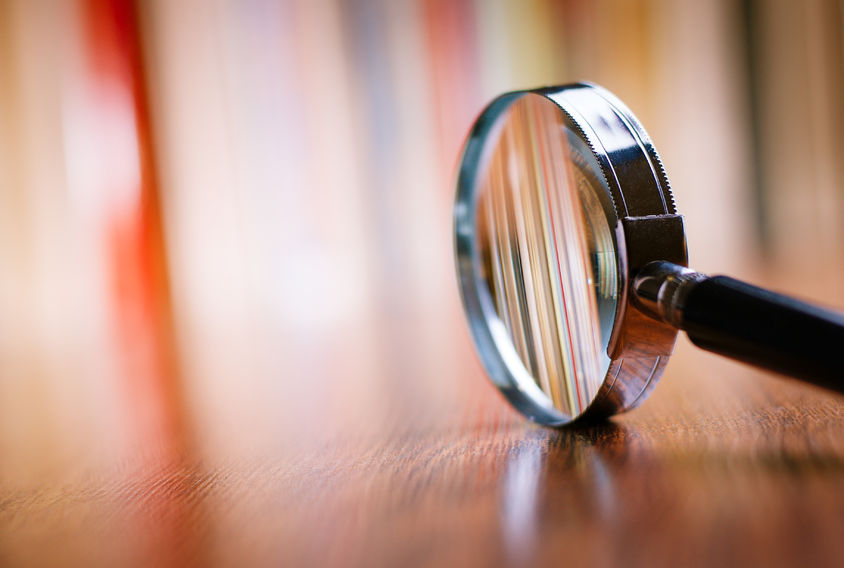 34105449 - close up single magnifying glass with black handle, leaning on the wooden table at the office.